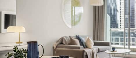 A modern hotel room with a round dining table, two mugs, a pitcher, and a plant.