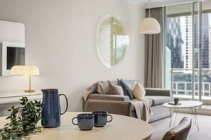 Ein modernes Hotelzimmer mit einem runden Esstisch, zwei Tassen, einer Karaffe und einer Pflanze.