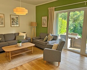 A modern living room with a sofa set, a coffee table, and a chair. There is a floor lamp and a painting on the wall.