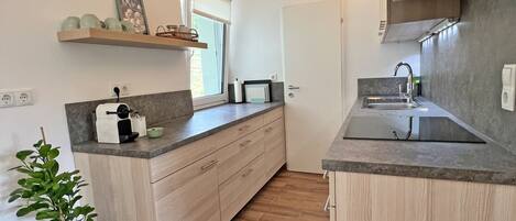 A modern kitchen with wooden cabinets, a built-in island, and a window providing natural light.