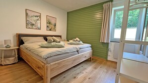 A room with a wooden bed, a nightstand, two wall-mounted paintings, and a green wall.