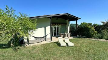 A single-story building with a covered patio area, a hammock, and two lounge chairs.