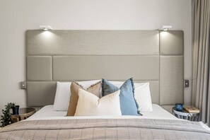 A bed with a headboard, multiple pillows, a bedside table, and a lamp. - Central City Studio: King Bed + Amazing Views! (Melbourne)