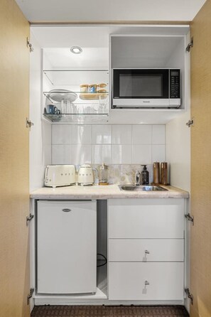 A compact kitchenette with a microwave, toaster, and small refrigerator. - Central City Studio: King Bed + Amazing Views! (Melbourne)