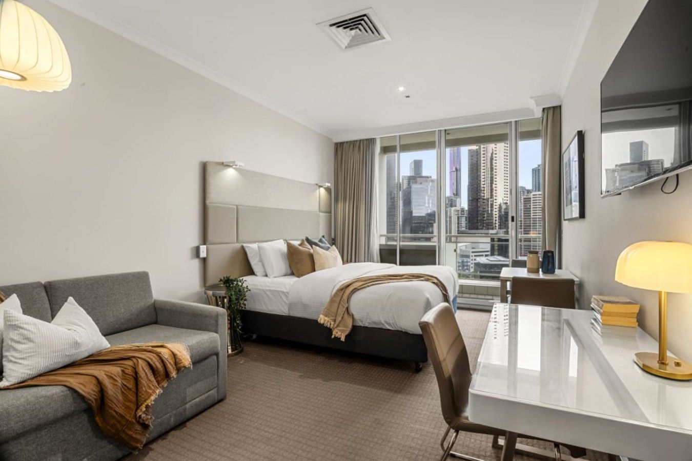 Ein Hotelzimmer mit Bett, einer Couch, einem Schreibtisch und Blick auf die Stadt.