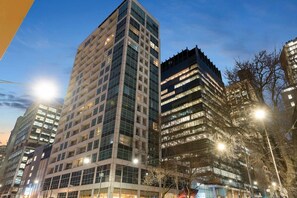 A high-rise building with multiple floors and large windows, surrounded by other buildings. - Central City Studio: King Bed + Amazing Views! (Melbourne)