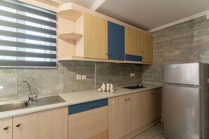 Une cuisine équipée d’un réfrigérateur en acier inoxydable, d’un évier et de meubles de rangement en bois.