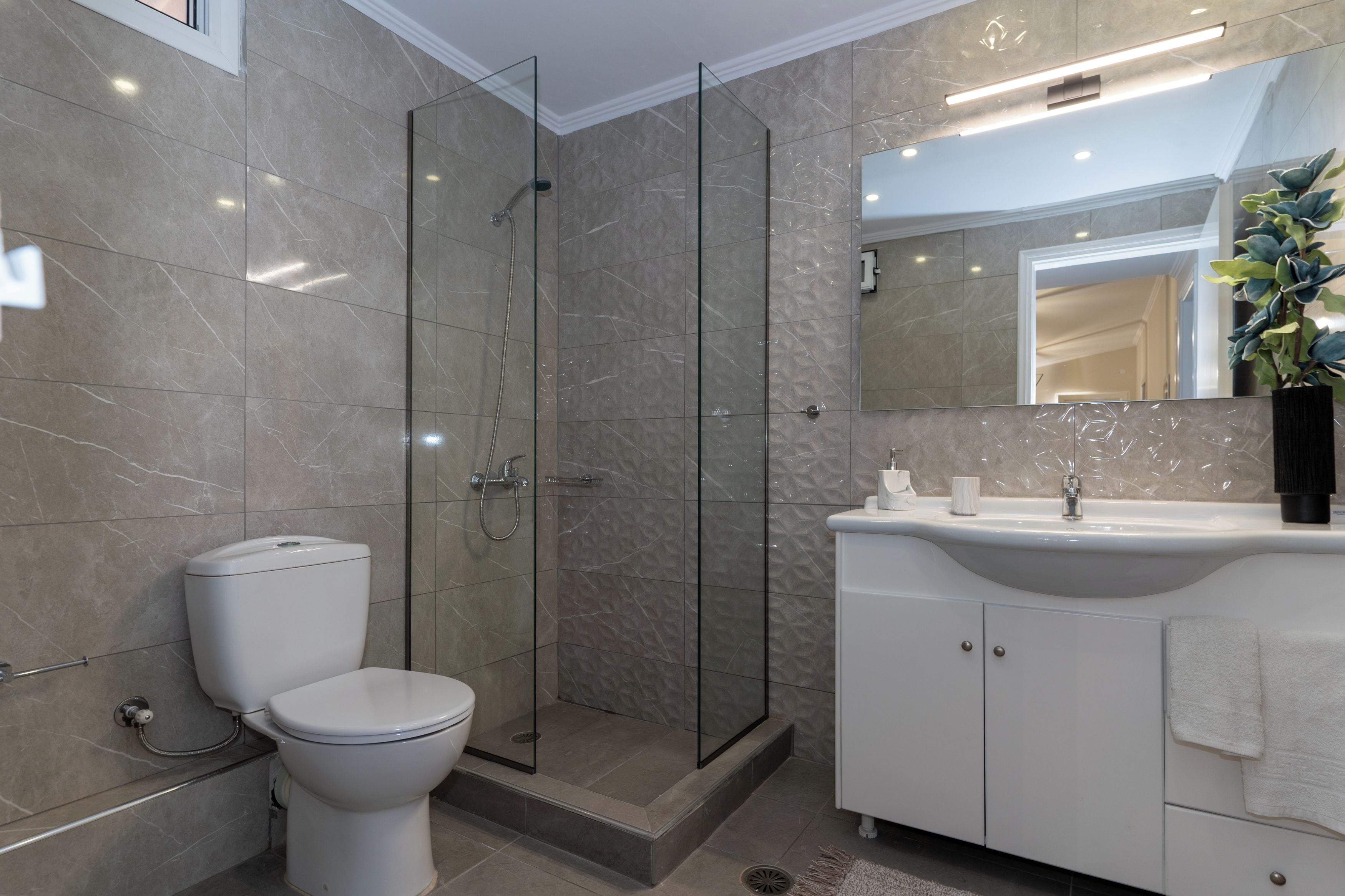 A modern bathroom with a glass-enclosed shower, a toilet, and a vanity with a sink.