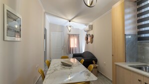 Une cuisine compacte dotée d’un plan de travail en marbre, de chaises jaunes, d’un four encastré et d’un luminaire suspendu moderne.