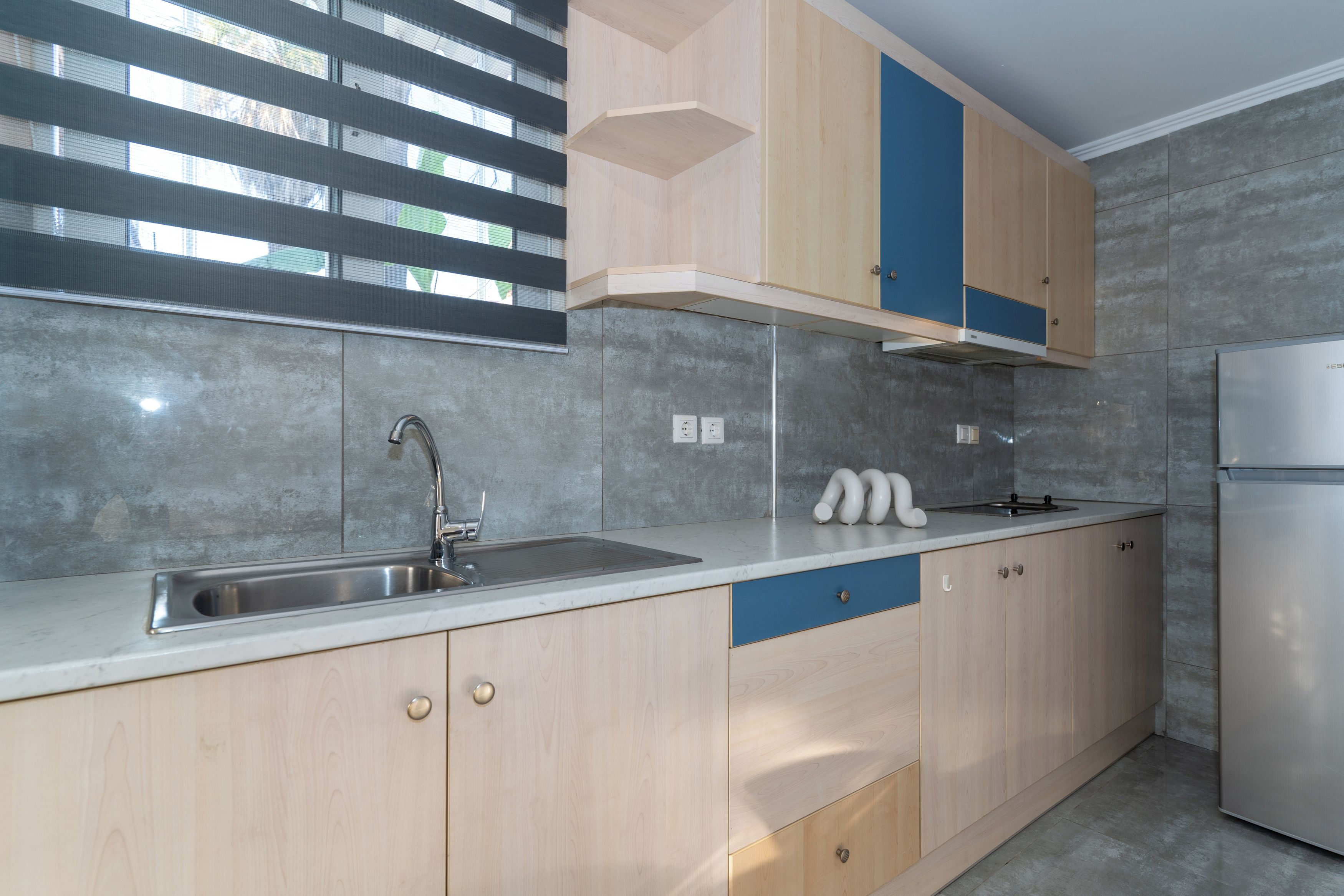 Een moderne keuken met een roestvrijstalen spoelbak, houten keukenkastjes en een ingebouwde oven.