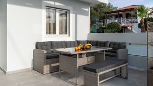 Une terrasse extérieure aménagée avec des meubles en osier, une table et un banc.