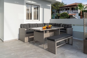 Eine Terrasse im Freien mit Korbmöbeln, einem Tisch und einer Bank.