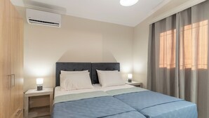 Un lit double avec une couvre-lit bleue, deux tables de chevet avec des lampes, une armoire en bois et une fenêtre avec des rideaux.