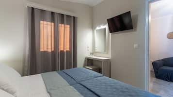 Quarto com cama, mesa de cabeceira, espelho, TV fixada na parede e porta que dá para outro espaço.