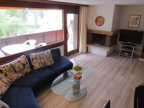 Una sala de estar con un sofá, una mesa de centro de vidrio, una chimenea y un televisor.