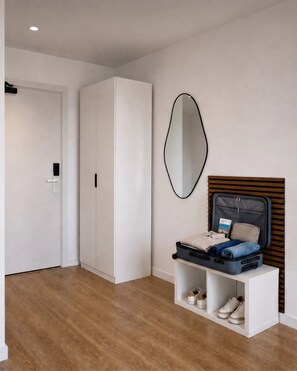 A modern room with a wardrobe, a mirror, a bed with a headboard, and a small table with a suitcase and shoes. - Essential Stays Madrid Carabanchel (Madrid)