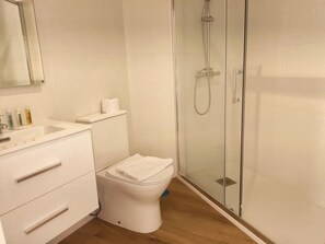 A modern bathroom with a toilet, sink, and glass-enclosed shower.