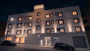 Un edificio de hotel con múltiples ventanas, un cartel que dice 'HOTEL' y un cartel para 'estancias esenciales'.