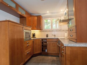 A kitchen with wooden cabinets, a microwave, a toaster, and a sink. - Chalet Gsür Appartement/Fewo, Bad, WC, 2 Schlafräume by Interhome (Adelboden)