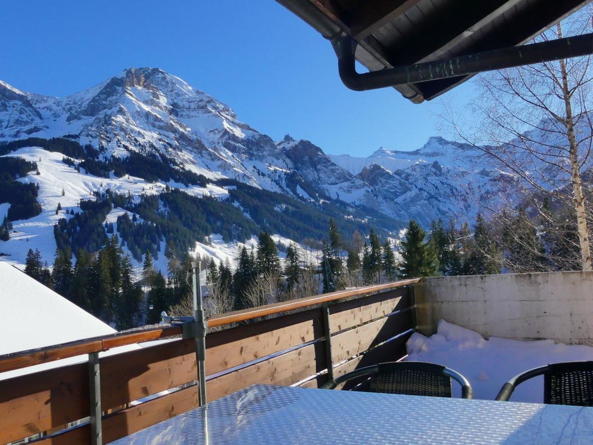 Vue sur la montagne depuis un espace extérieur aménagé, abrité et doté d’une table et de chaises.