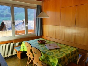 Ein Zimmer mit Tisch, Stühlen, einem Fenster und Blick sowie einer Heizung.