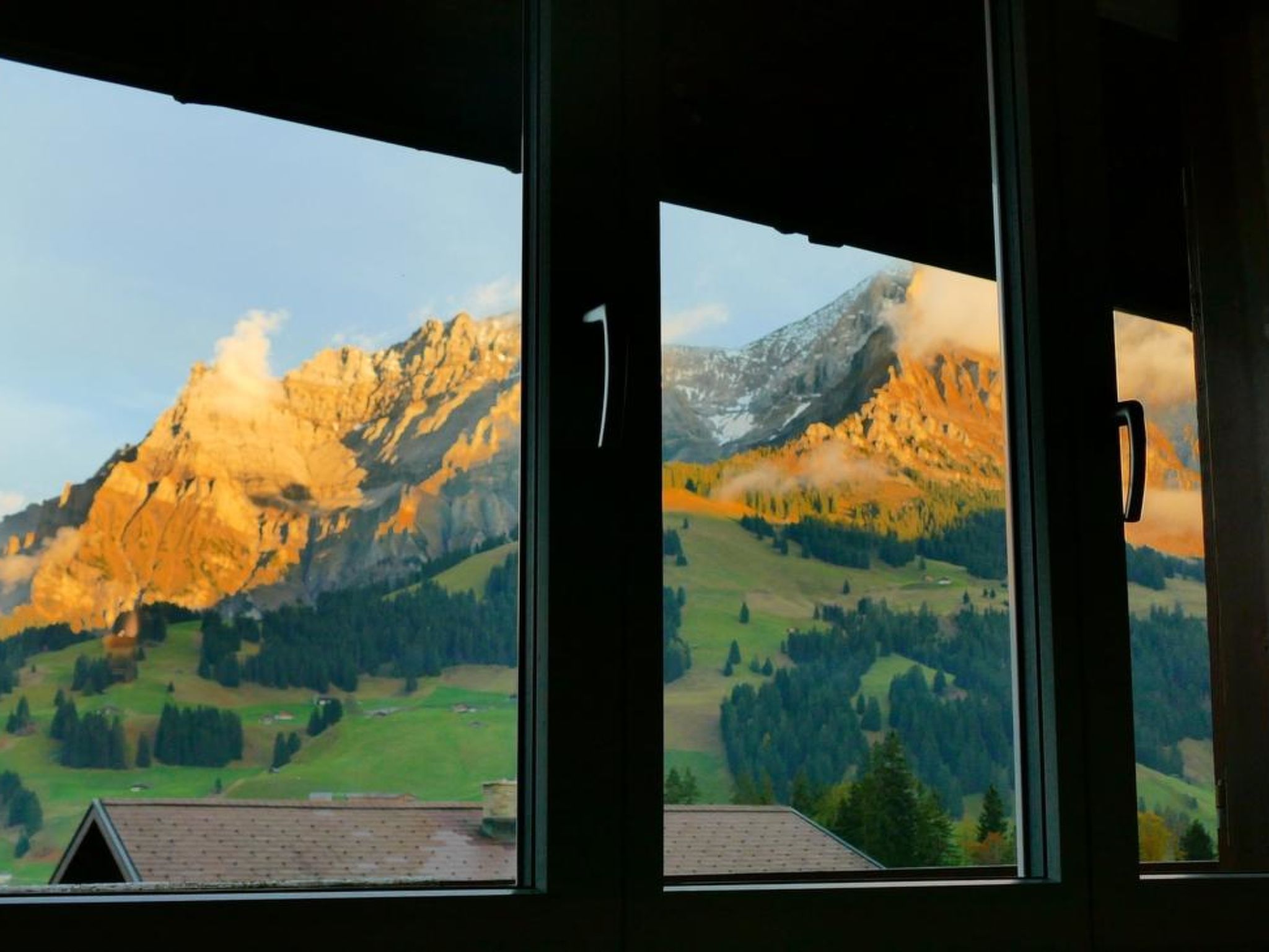 A view of a mountain range through a window with a handle.