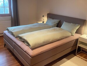 A double bed with a headboard, a bedside table, and a lamp. - Haus Abäsonne Appartement/Fewo, Bad, WC, 1 Schlafraum 2.5 Zimmerwohnung by Interhome (Adelboden)