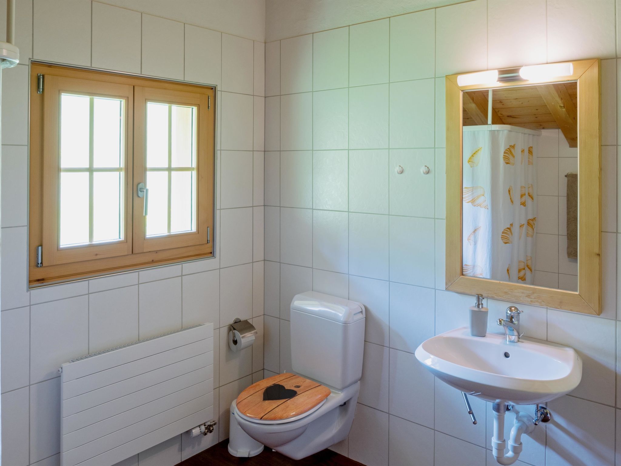 Ein Badezimmer mit Toilette, Waschbecken, Fenster und Heizkörper.