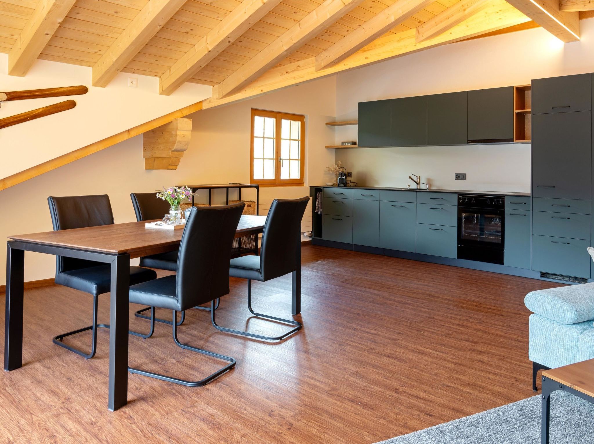 A modern kitchen with a built-in oven and a dining area with a wooden table and chairs.