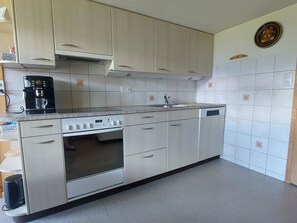 Eine Küche mit Backofen, Kaffeemaschine und weißen Schränken.