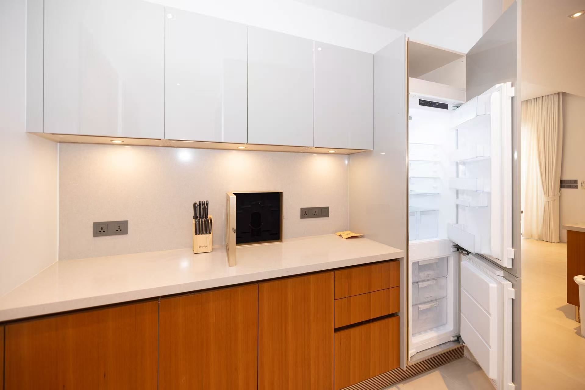A modern kitchen with white cabinets, a wooden countertop, and a built-in oven.