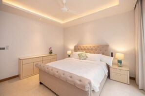 A bedroom with a large bed, bedside lamps, a ceiling fan, and a nightstand.