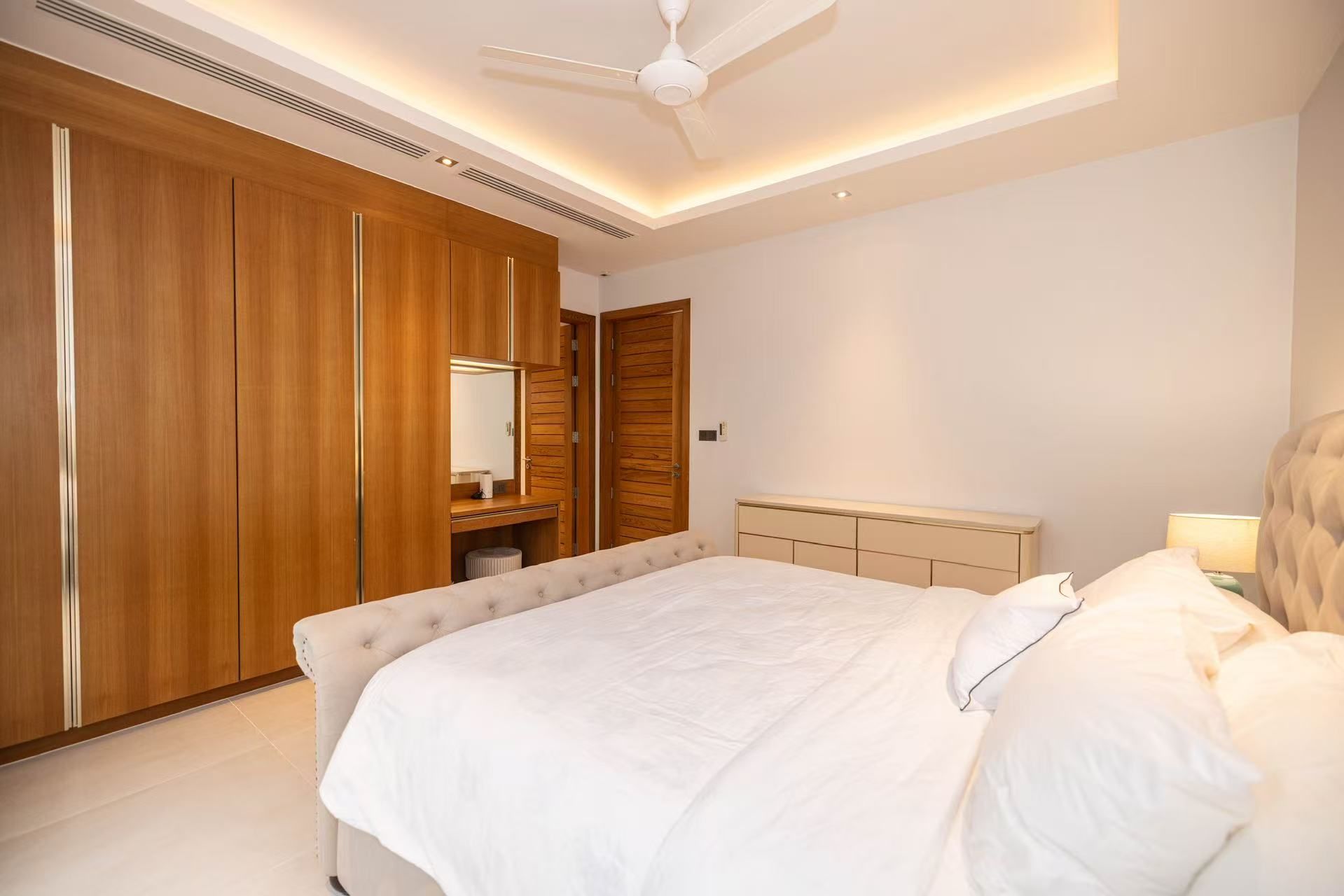 A bedroom with a bed, a wardrobe, a mirror, and a ceiling fan.