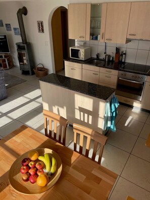 A modern kitchen with a central island, wooden chairs, and a fruit bowl. - Am Gilsbach 2 Appartement/Fewo, Dusche und Bad, WC, 2 Schlafräume by Interhome (Adelboden)