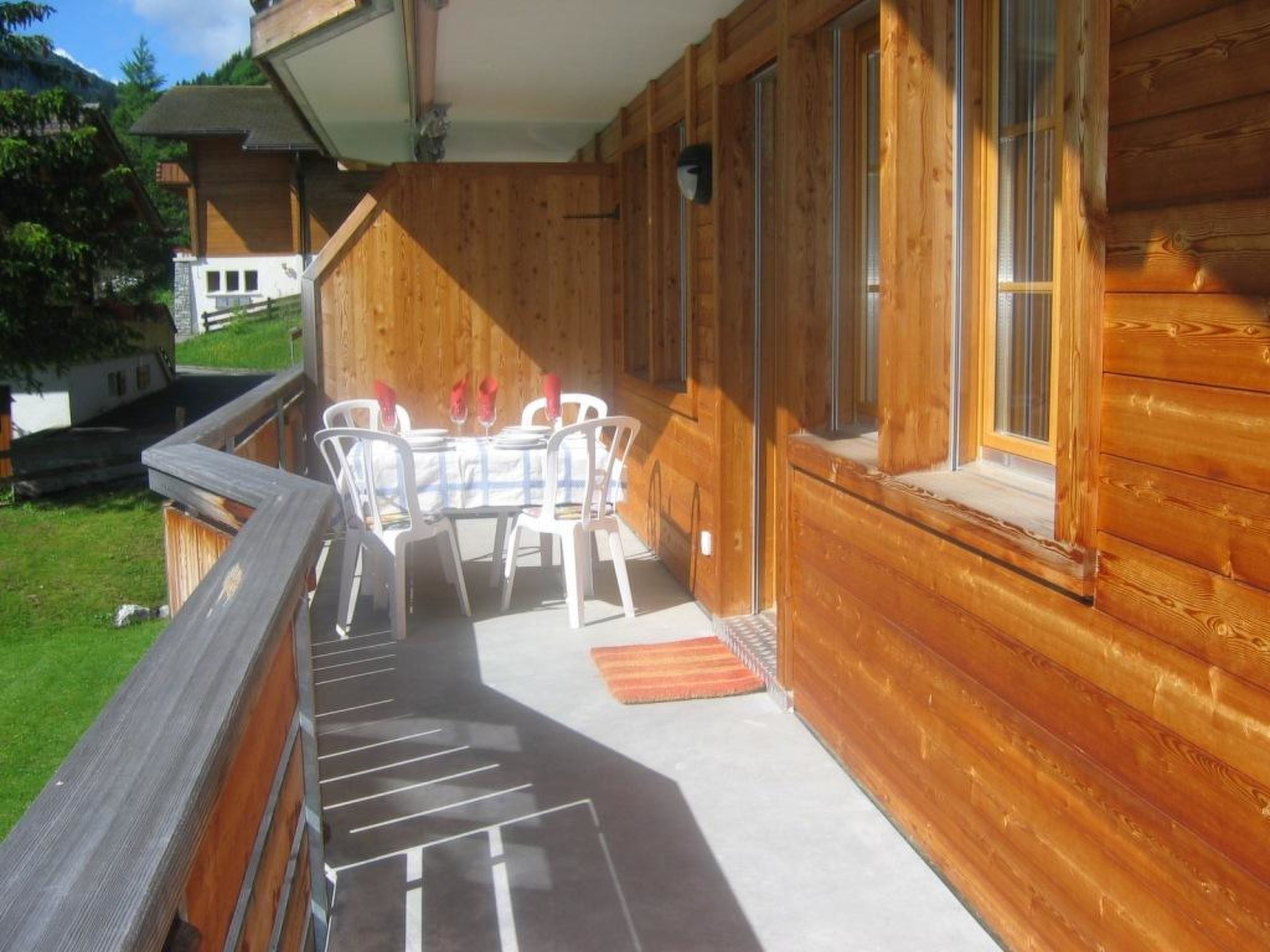 A wooden cabin with a balcony, a table with chairs, and a window.