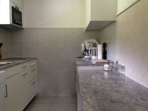 A kitchen with a microwave, coffee maker, and a coffee pot on the counter. - Bärgrose Appartement/Fewo, Bad, WC, 3 Schlafräume 4-Zimmerwohnung by Interhome (Adelboden)