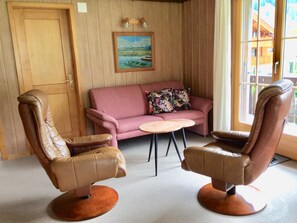 A room with two leather chairs, a pink sofa, a small round table, and a painting on the wall. - Bärgrose Appartement/Fewo, Bad, WC, 3 Schlafräume 4-Zimmerwohnung by Interhome (Adelboden)