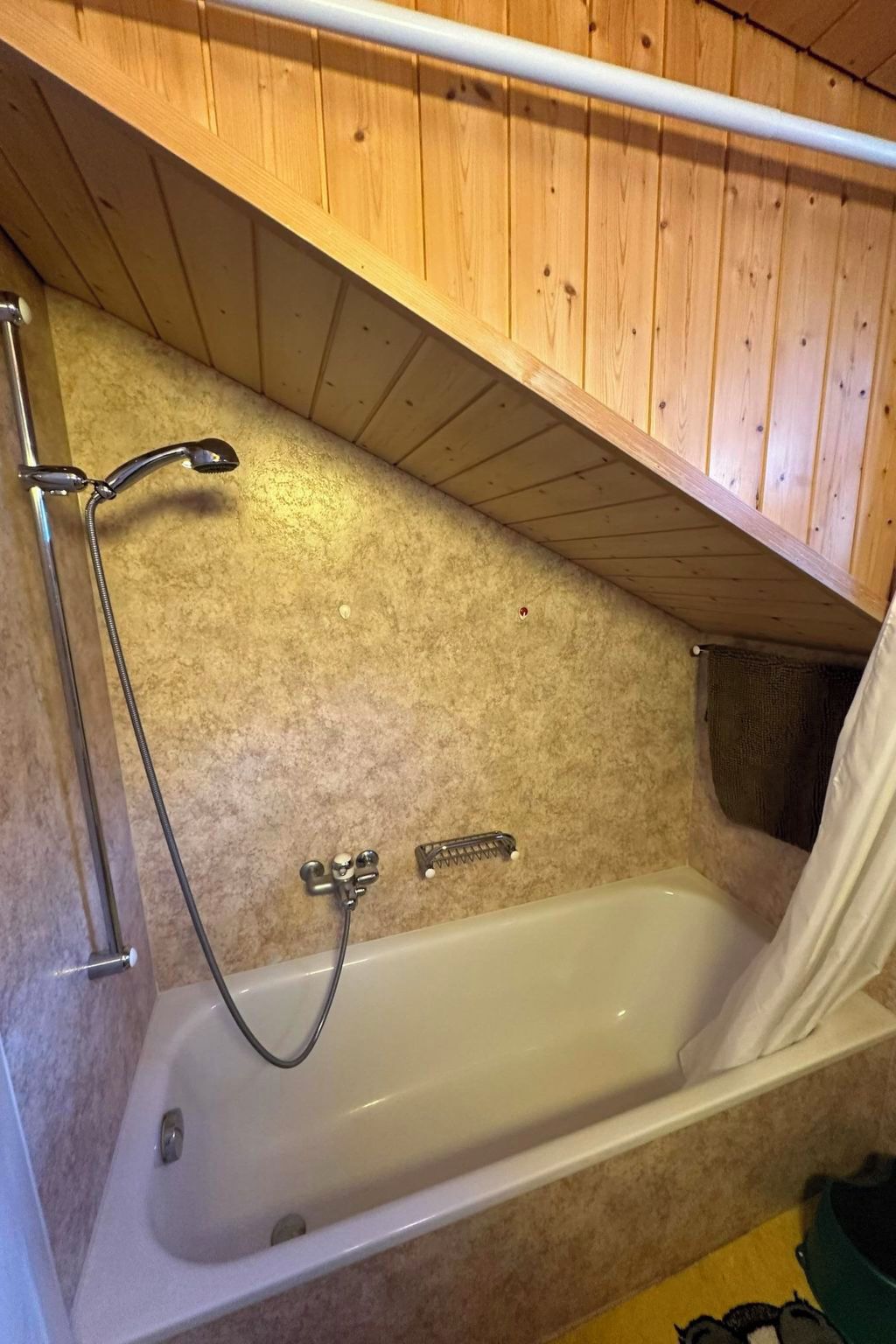 A bathroom with a bathtub, shower, and wooden ceiling.