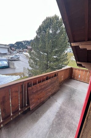 Ein Balkon mit Blick auf eine verschneite Straße und einen großen Baum.