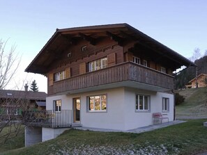 Ein zweistöckiges Holzhaus mit Balkon, einer kleinen Veranda und einem Rasen.