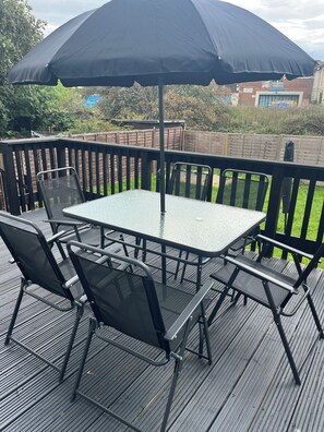Une terrasse avec une table et des chaises, un parasol et une clôture en bois.