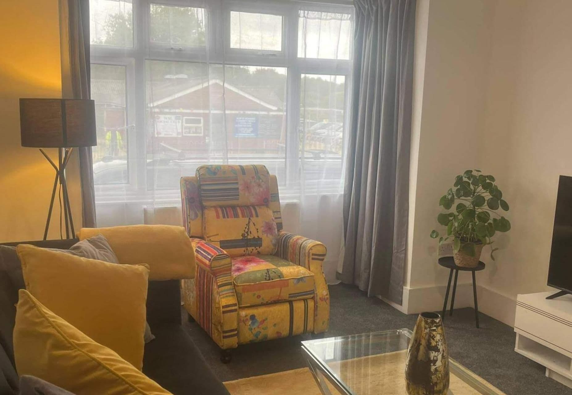 Ein Wohnzimmer mit einer Couch, einem Sessel und einem kleinen Tisch mit einer Vase.