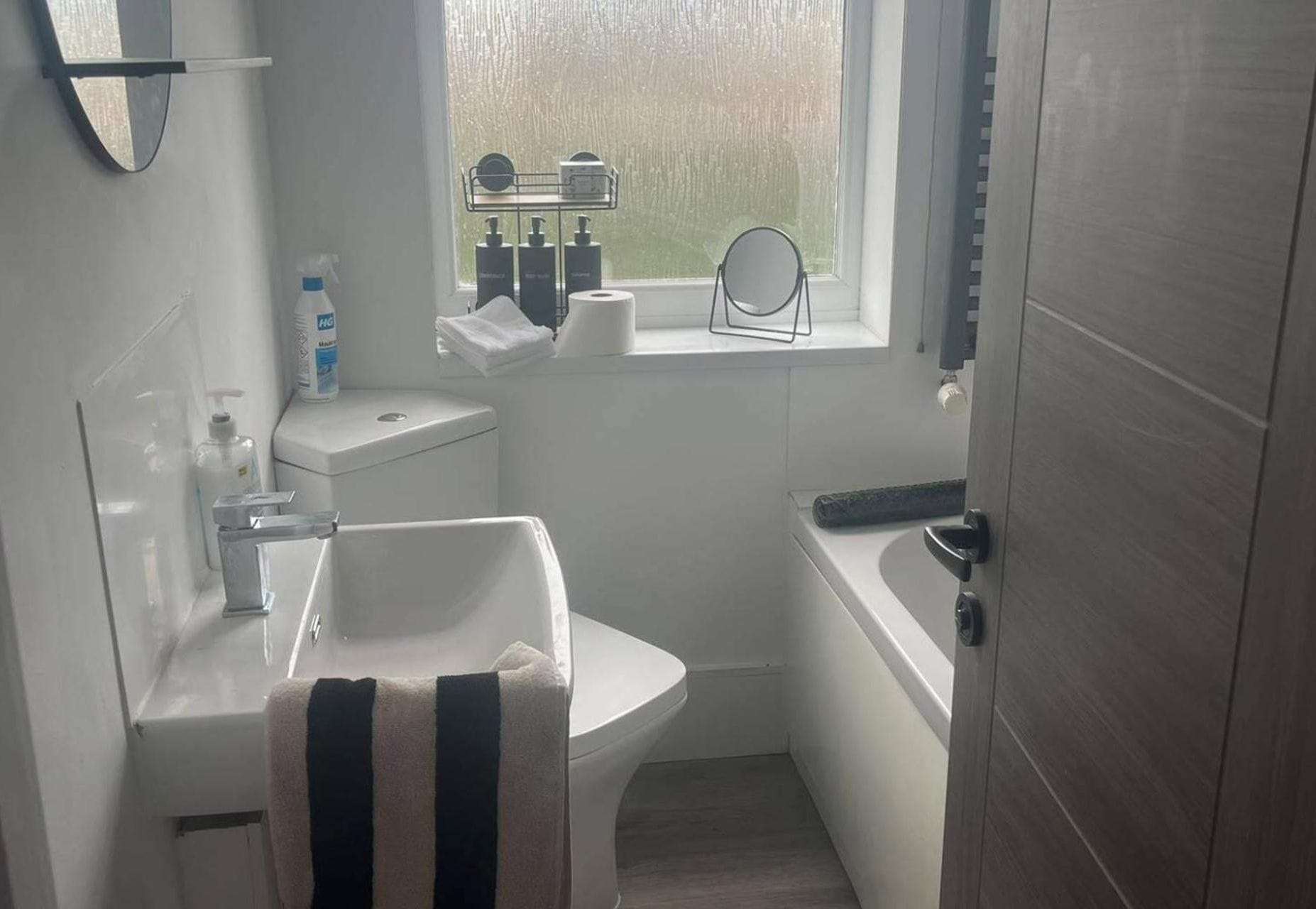 A bathroom with a toilet, sink, and bathtub. There is a window with a view of trees outside.