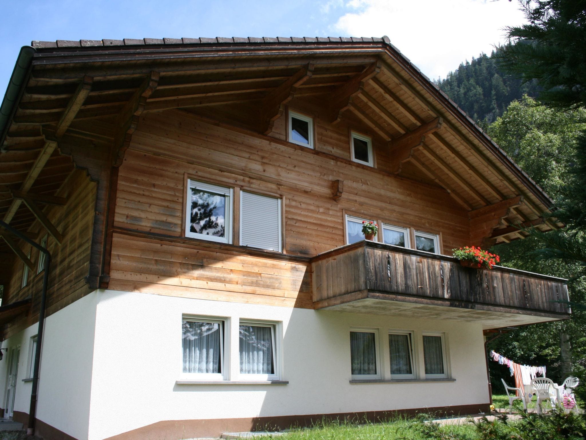 A two-story wooden house with a balcony, windows, and a white lower section.