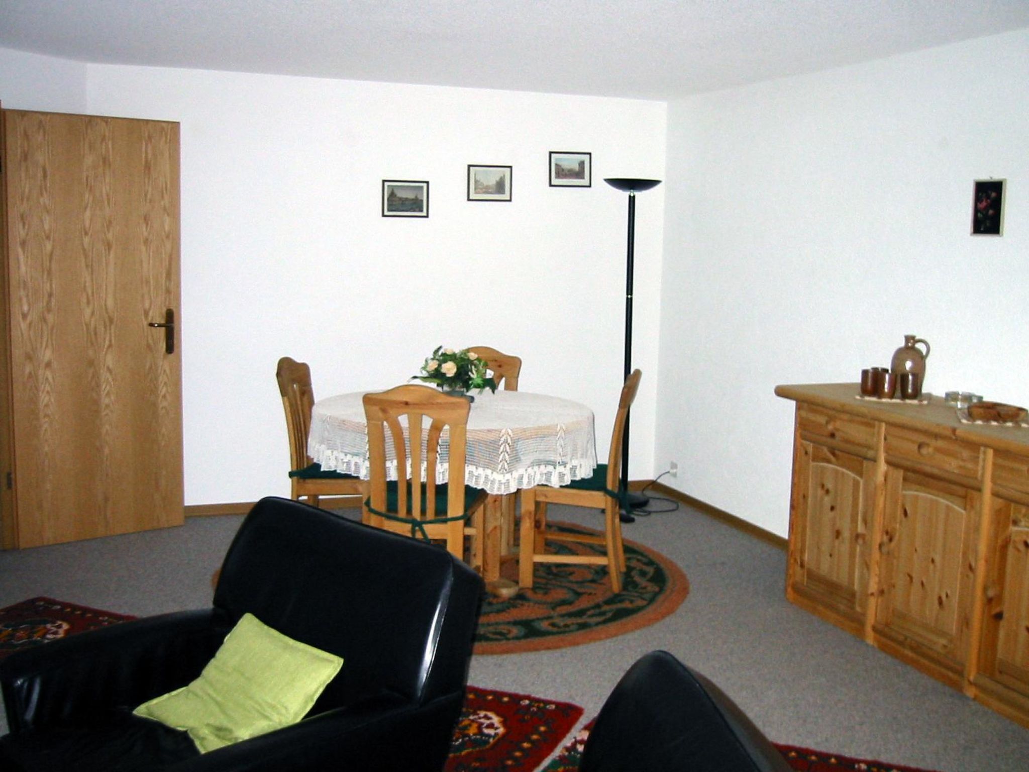 Une pièce comprenant une table à manger, des chaises, un buffet et un canapé en cuir noir.
