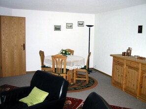 A room with a dining table, chairs, a cabinet, and a black leather sofa. - Chalet im Ahori Appartement/Fewo, Dusche oder Bad, WC 3-Zimmerwohnung by Interhome (Kandersteg)