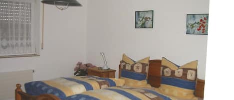 Une chambre à coucher avec un lit en bois, une table de chevet, une lampe et deux tableaux accrochés au mur.