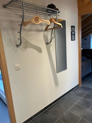 A hallway with a metal rack holding wooden hangers, a wall-mounted light switch, and a framed picture. - Am Gilsbach Appartement/Fewo, Dusche und Bad, WC, 2 Schlafräume by Interhome (Adelboden)