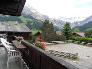 A balcony with a view of a mountainous landscape, wooden railings, and a table with flowers. - Sunnegruess Appartement/Fewo, Dusche, WC, 2 Schlafräume 3-Zimmerwohnung by Interhome (Adelboden)