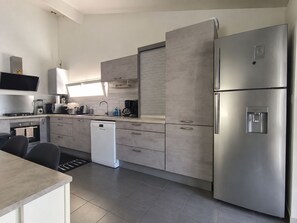 A modern kitchen with stainless steel appliances, a dishwasher, and a built-in oven. - The Family Home (Chartres)